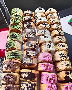 a tray filled with various delicious breads and cakes. are all topped with a variety of colorful frostings, sprinkles.