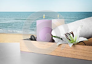 Tray with flower and spa supplies on table against seascape