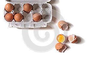 Tray of fresh raw eggs and broken egg shell on white isolated background.