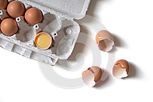 Tray of fresh raw eggs and broken egg shell on white isolated background.