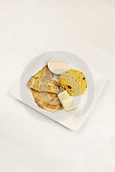 A tray of fried flat fish with a bowl of rice with vegetables,