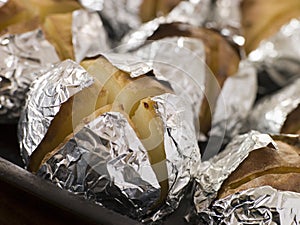 Tray of Jacket Potatoes Wrapped in Foil photo