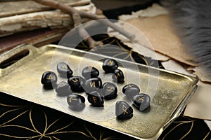 Tray with many black rune stones on divination mat, closeup