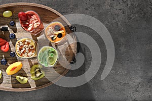 Tray with many different delicious smoothies and ingredients on grey table, top view. Space for text