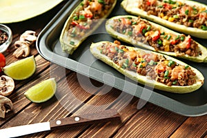 Tray with meat stuffed zucchini boats on wooden table, closeup