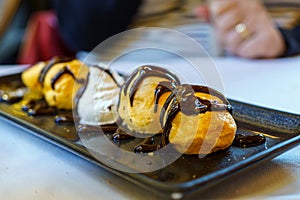 Tray of profiteroles, are a type of French pastry made with a puff pastry dough filled with pastry cream. They are usually served