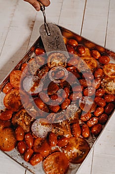 a tray of sliced up tomato and garlic with someone holding a knife