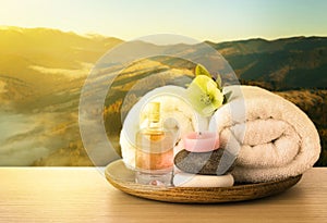 Tray with spa supplies on wooden table against beautiful mountain landscape in morning, space for text