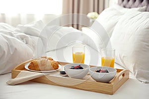 Tray with tasty breakfast on bed