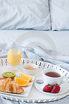 Tray with tasty breakfast on a bed