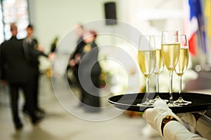 A tray with three glasses of champagne. Waiter holding a tray with a champagne glass