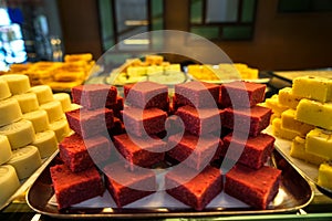 Trays full of stack colorful red velvet Indian sweet dessert in bakery showcase