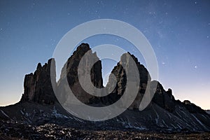 Tre Cime di Lavaredo at night over starry sky.