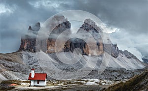 Tre Cime park in Dolomites, Italy. Mystical landscape with rocky mountains and beautiful church at dusk, Italian alps