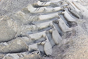 A tread mark from a wheel of a construction vehicle on the ground. Heavy machinery imprint. Dried mud vehicle wheel shape