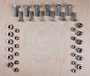 Treaded fasteners bolts and nuts at wooden background with copy space for your own text