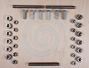 Treaded fasteners bolts and nuts at wooden background with copy space for your own text