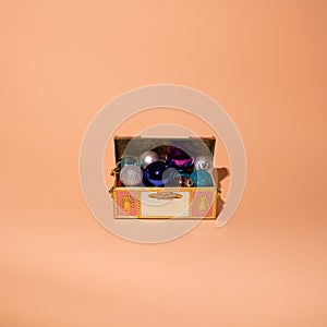 Treasure chest with colorful Christmas balls and decorations on velvet with gold ornaments. Flat lay concept