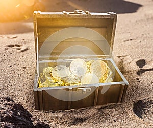 Treasure chest filled with bitcoins surrounded by golden glow partially burried in sand