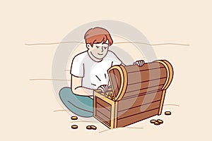 Treasure hunter boy found wooden chest with gold and is sitting on beach looking at prey