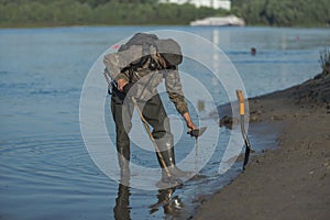 Treasure hunter is looking for a metal detector in the river