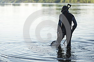 Treasure hunter is looking for a metal detector in the river