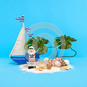 Treasure island concept: toy sailing boat and captain on sand shore with message bottle, shells, starfish and monstera