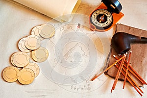 Treasure map, gold coins, compass, smoking accessories, old papers on the desk