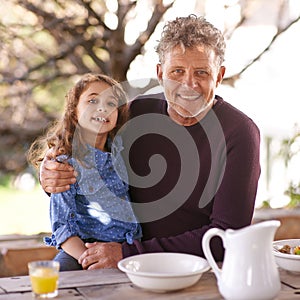 He treasures his granddaughter. Portrait of a little girl and her grandfather having breakfast together outside.