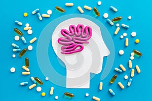 Treat brain diseases. Head with plastiline meanders and pills on blue background top view