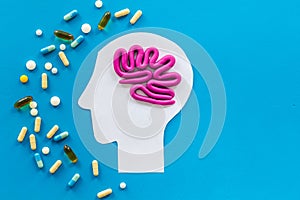 Treat brain diseases. Head with plastiline meanders and pills on blue background top view copy space