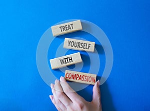 Treat yourself with compassion symbol. Concept words Treat yourself with compassion on wooden blocks. Beautiful blue background.