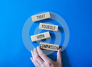 Treat yourself with compassion symbol. Concept words Treat yourself with compassion on wooden blocks. Beautiful blue background.