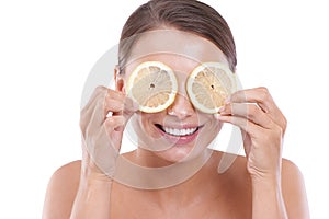 Treating her eyes with citrus. A young woman holding a slice of lemon infront of each eye.