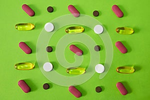 A treatment for ailment. Studio shot of an assortment of medication against a green background.