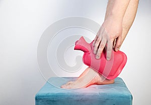 Treatment of arthritis of the ankle joint with a heating pad with hot water. Copy space for text