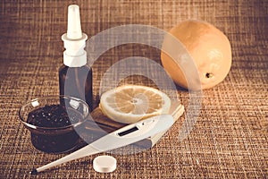 Treatment of colds and flu. Various medications, thermometer, cold pills, throat spray, nasal drops, lemon on a brown background.