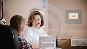 A treatment in eye clinic - mature woman doctor talking to the boy and giving him an eye shield
