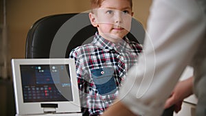 A treatment in eye clinic -a woman doctor checking boy`s vision using a big special device