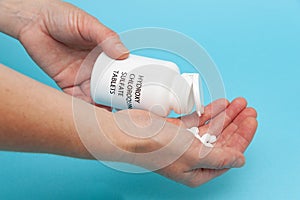 Treatments for Coronavirus COVID-19: Hydroxychloroquine Sulfate - White plastic packaging bottle in the hands with tablets.