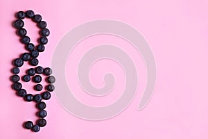 Treble clef made of bilberries on color background, top view with space for text.