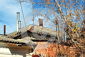 Tree with bare branches on the background of an old historical house with red walls and a lot of chimneys on the roof.