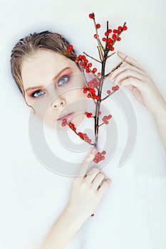 Tree Branch with red berries in hand Woman blonde wet hair bright beautiful art makeup portrait closeup. Perfect facial skin