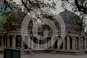 A tree branches create some dramatic view of monument at hauz khas memorial from the side of the lawn at winter foggy morning