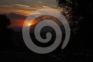 Tree branches heading towards the sun hiding behind volcano at dusk in Puebla Mexico dramatic Twilight