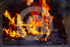 Tree branches and wooden boards burning inside a clay oven