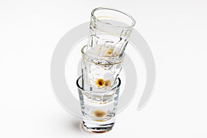 Three dirty empty glasses in a row on white background.