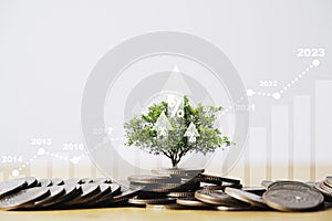 Tree growing on coins stacking with up arrow and increasing graph for money saving and deposit growth from investment profit ,