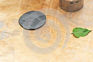 Kid craft imprint of a green leaf in black clay.