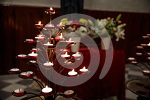 Tree like candle holder in Italian church. Warm candle light in a darch catholic church